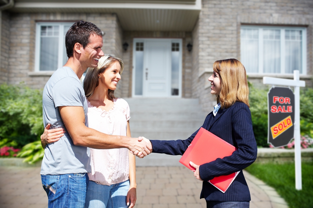 A couple shaking hands, with a lady standing in front of a house with a 'sold' sign