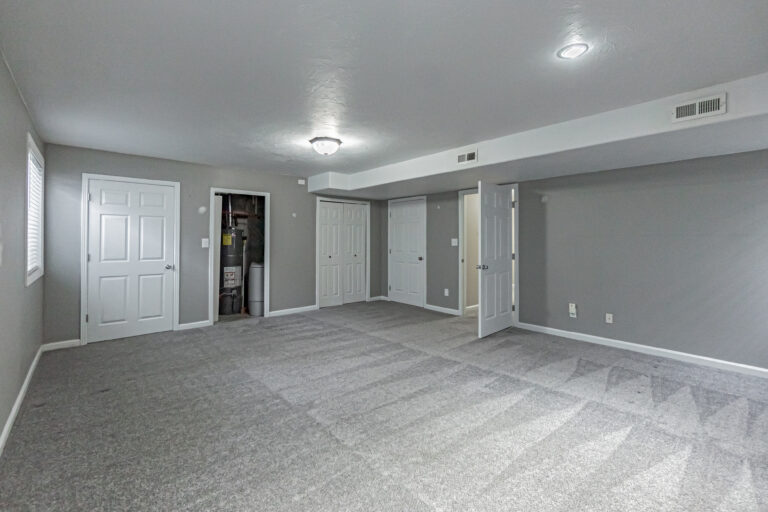 Empty room with doors and carpet, potential for furnishing.